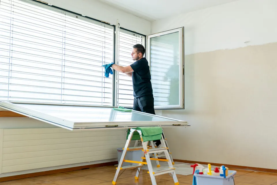 Agent de nettoyage lavant une fenêtre dans un appartement vidé à Lausanne