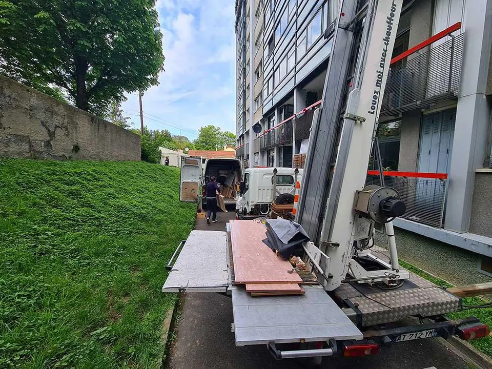 Monte-meubles et camion chargés de planches au pied d'un immeuble
